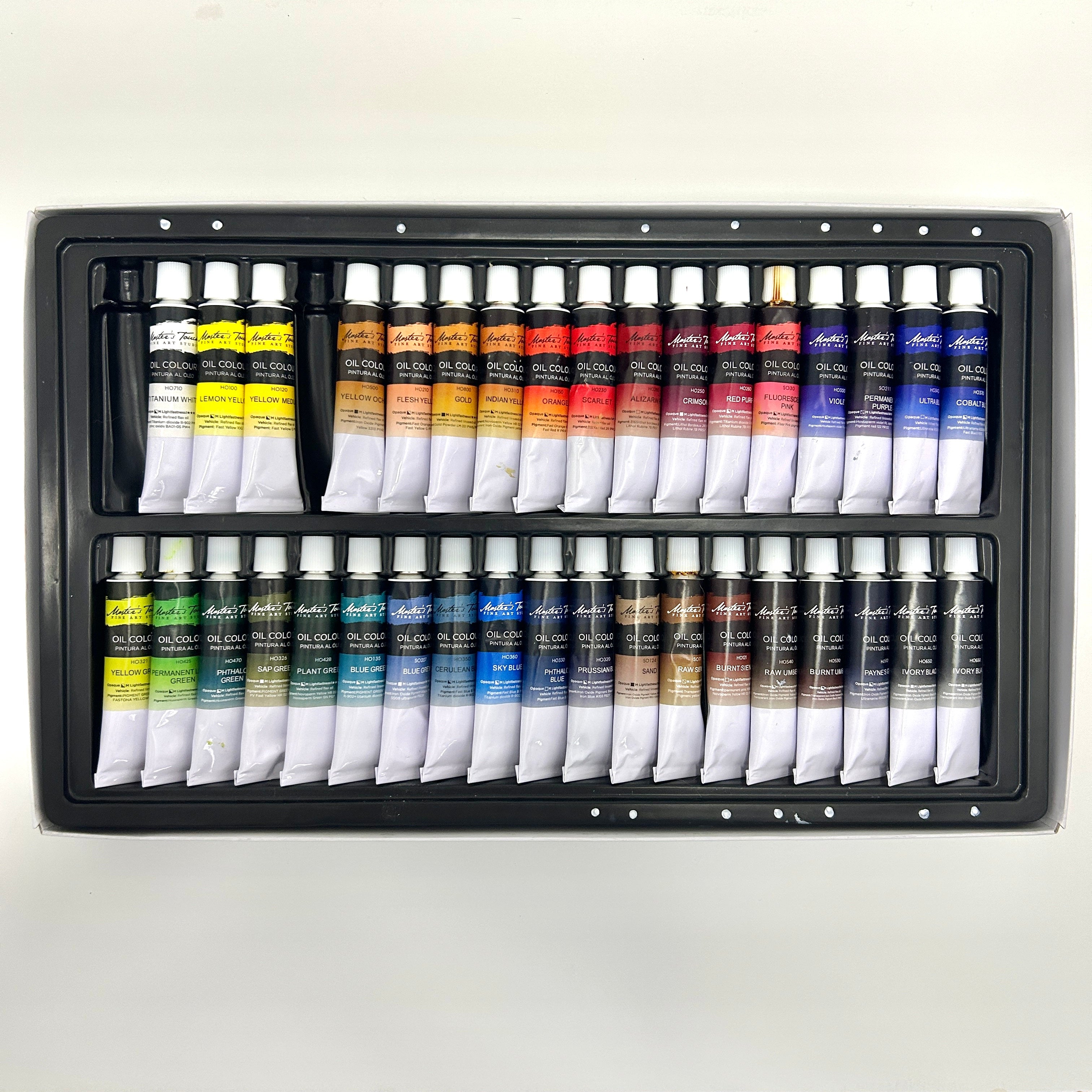 Set of art supplies including paint tubes and brushes in a black case on a white background