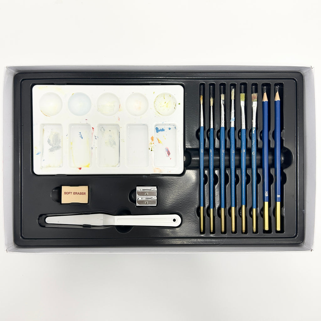Art supply set with brushes, pencils, and a palette in a black case on a white background
