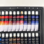 Set of oil paint tubes in a black tray on a white background