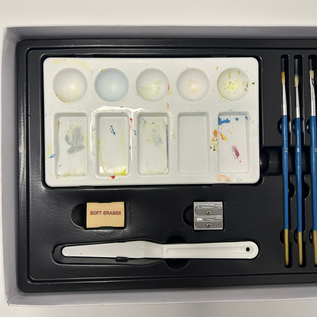 Art supply set with paint palette, brushes, and other tools on a white background