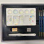 Art supply set with paint palette, brushes, and other tools on a white background